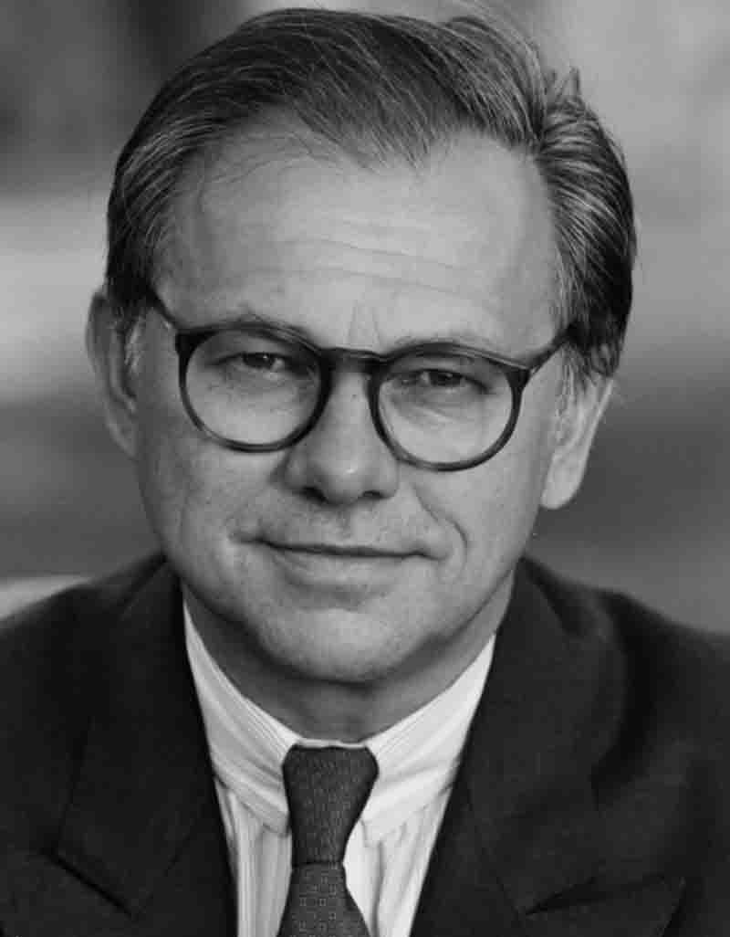 Schwarz-Weiß-Porträt des Verlegers Hubert Burda mit runder Brille, Anzug und Krawatte, der direkt in die Kamera blickt.